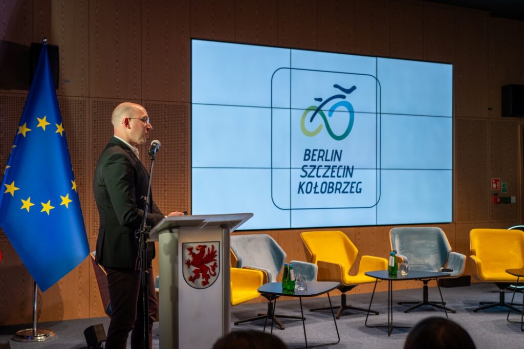 Wicemarszałek województwa Jakub Kowalik prezentuje logo trasy rowerowej Berlin - Szczecin - Kołobrzeg