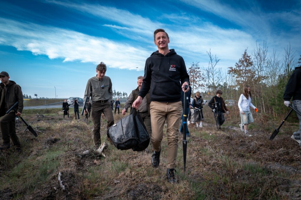Marszałek Województwa Zachodniopomorskiego Olgierd Geblewicz, zastępca dyrektora ds. gospodarki leśnej Regionalnej Dyrekcji Lasów Państwowych w Szczecinie Maciej Szabla i młodzież podczas sadzenia lasu 15 kwietnia 2025 r.