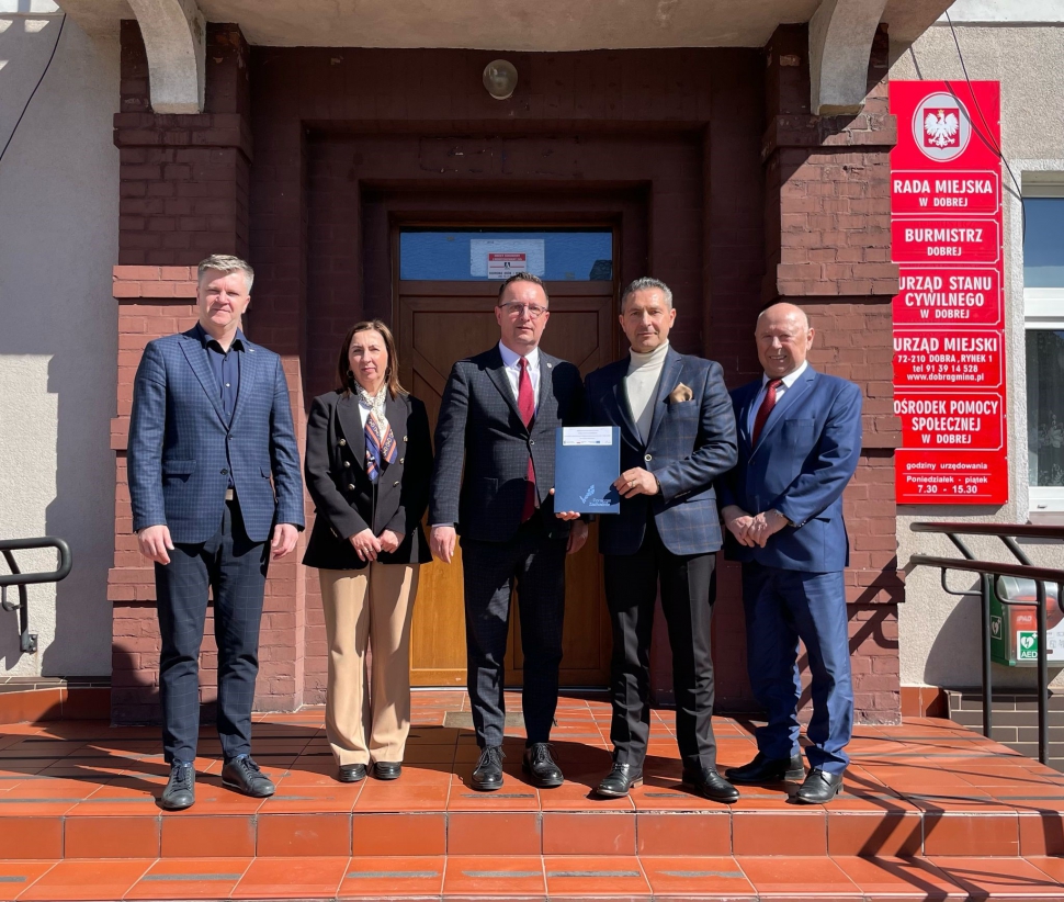 Członek Zarządu Województwa Zachodniopomorskiego Bogdan Jaroszewicz oraz Burmistrz Dobrej Krzysztof Wrzesień wraz z osobami towarzyszącymi na tle wejścia do Urzędu Gminy Dobra (powiat łobeski)