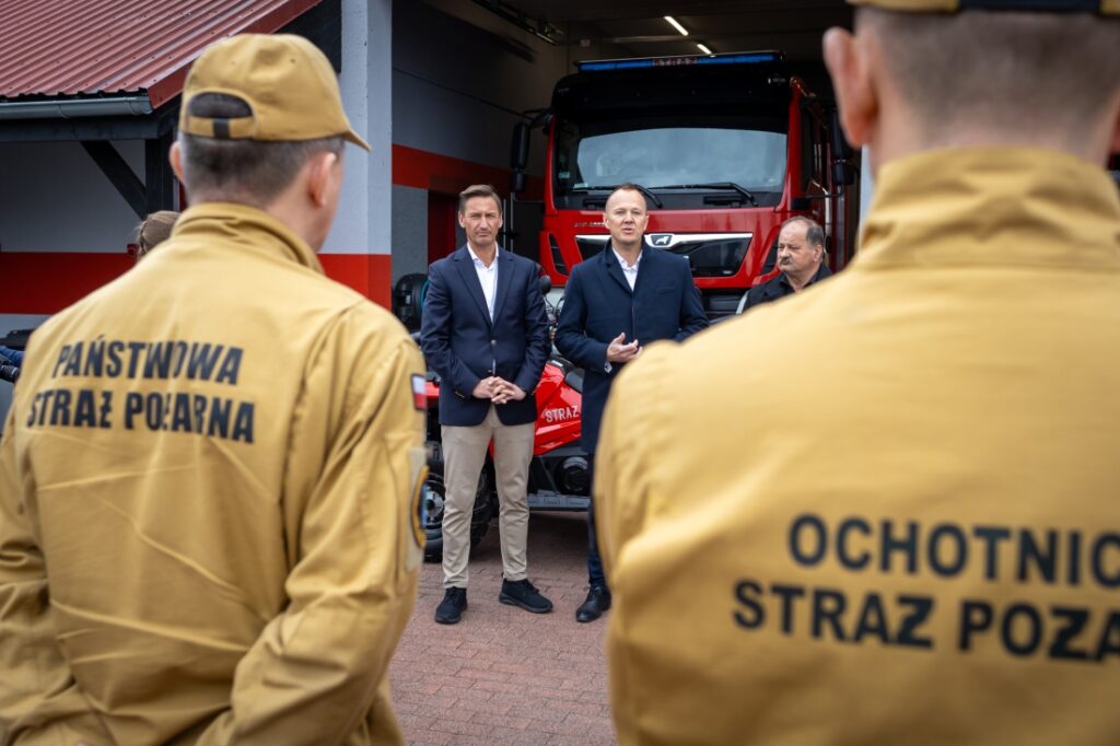 Marszałek Województwa Zachodniopomorskiego Olgierd Geblewicz z osobami towarzyszącymi stoją przy przed remizą OSP Lubczyna