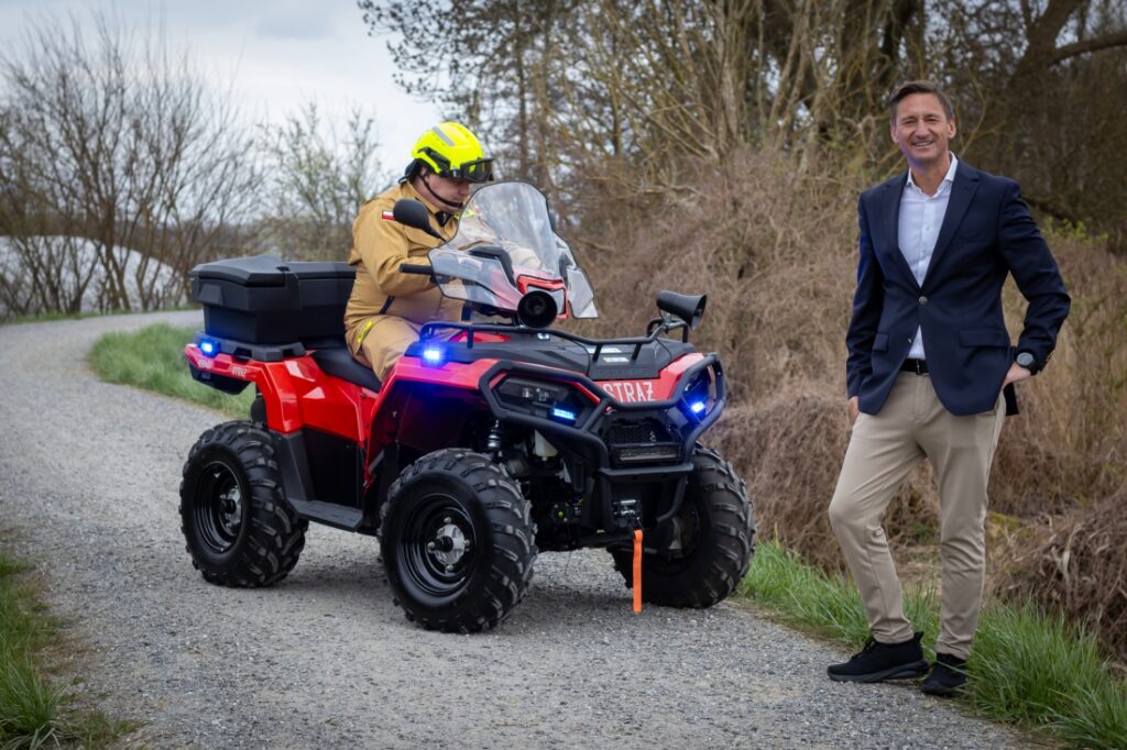 Marszałek Województwa Zachodniopomorskiego Olgierd Geblewicz stoi na ścieżce rowerowej Blue Velo. Obok niego znajduje się strażak z OSP Lubczyna na nowym quadzie.