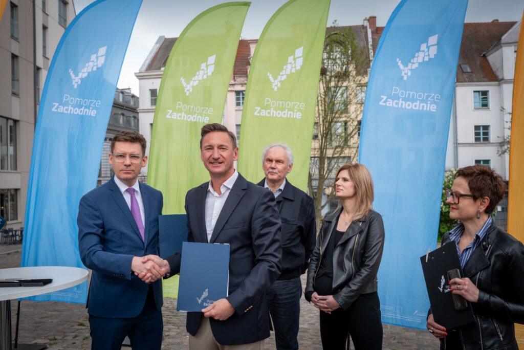 Marszałek Województwa Zachodniopomorskiego Olgierd Geblewicz, zastępca prezydenta Szczecina Michał Przepiera, w towarzystwie innych osób podczas podpisywania umowy o dofinansowanie przebudowy Placu Orła Białego w Szczecinie, 22.04.2025