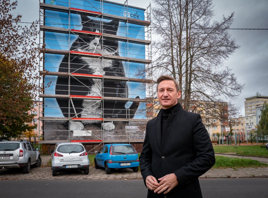 Marszałek Województwa Zachodniopomorskiego Olgierd Geblewicz na tle ekologicznego muralu przedstawiającego kota Gacka. Powstał na ścianie budynku przy ul. Rugińskiej 34-35 w Szczecinie. Na Pomorzu Zachodnim powstanie 11 ekomurall, pochłaniających zanieczyszczenia powietrza...