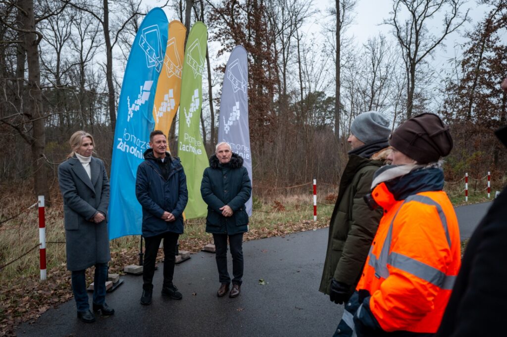 Grupa osób, m. in. Marszałek Olgierd Geblewicz i dyrektor ZZDW Waldemar Wejnmerowski, podczas przekazania terenu pod budowę drogi rowerowej.