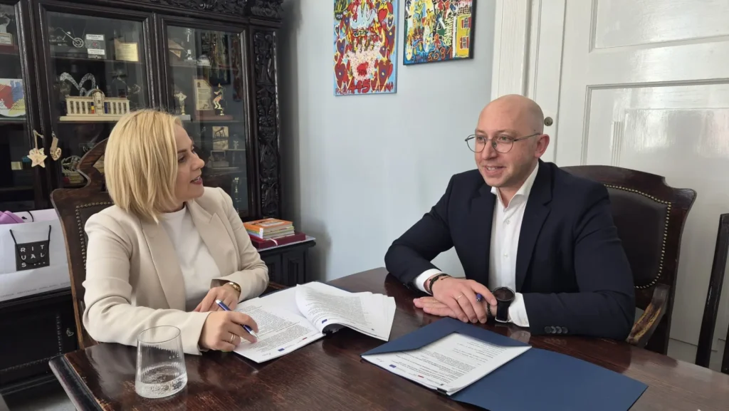 Emilia Bury, burmistrz miasta Białogard, oraz Jakub Kowalik, wicemarszałek województwa zachodniopomorskiego, siedzą za stołem i podpisują umowę o dofinansowanie projektu